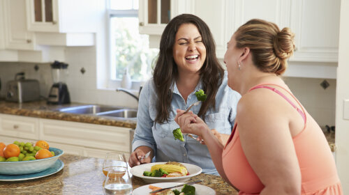 33519255 — two overweight women on diet eating healthy meal in kitchen