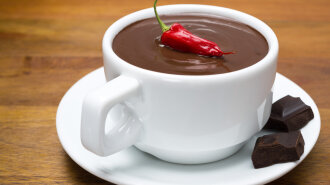 cup of hot chocolate with chili peppers on a wooden background,