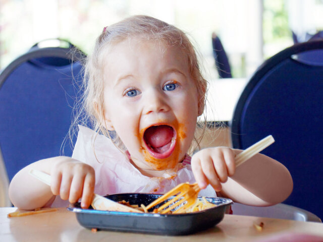 37919969 — funny little blond girl eating pasta and making a mess