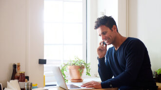 Man using mobile phone with laptop at cafe