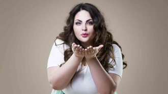 Plus size fashion model sends air kiss, fat woman on beige background, overweight female body