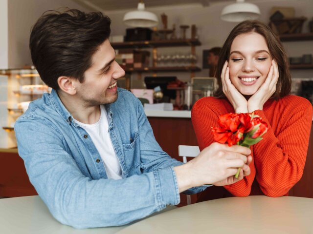 Photo of attractive man giving flowers to his beautiful woman, w