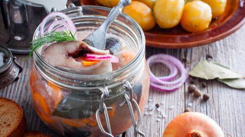 Swedish traditional marinated herring with onions and carrots in a glass jar, selective focus