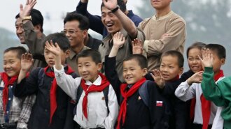 North Korean children and their parents wave to Chinese residents as they take tour on boat on Yalu 