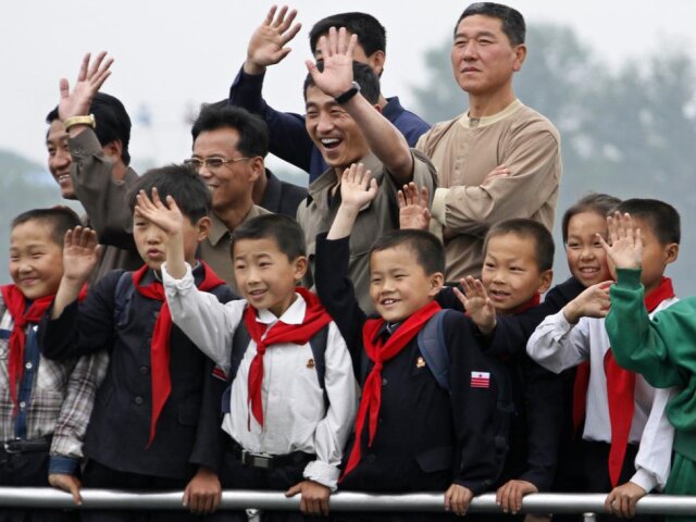 North Korean children and their parents wave to Chinese residents as they take on tour boat on Yalu 