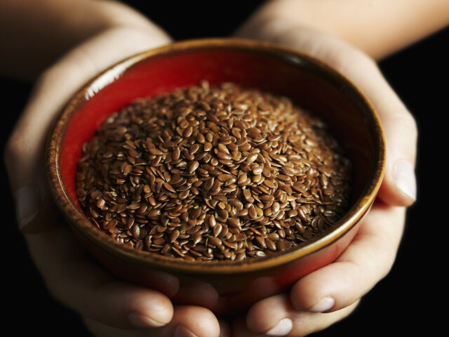 hands holding bowl of flax seed