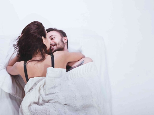 Beautiful loving couple is posing in a bed