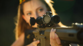 Girl with a gun for trap shooting aiming at a target