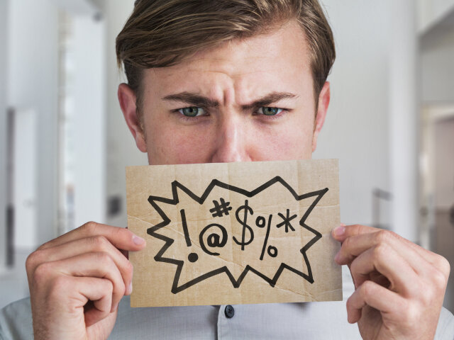 Man holding swear word sign in front of his mouth