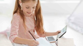 Smart schoolgirl working on home assignment
