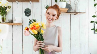 Cheerful young woman with pretty bouquet looking camera
