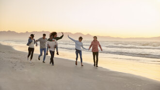 Group Of Friends Having Fun Running Along Winter Beach Together
