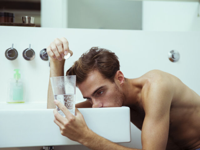Hungover man watching effervescent tablets in bathroom