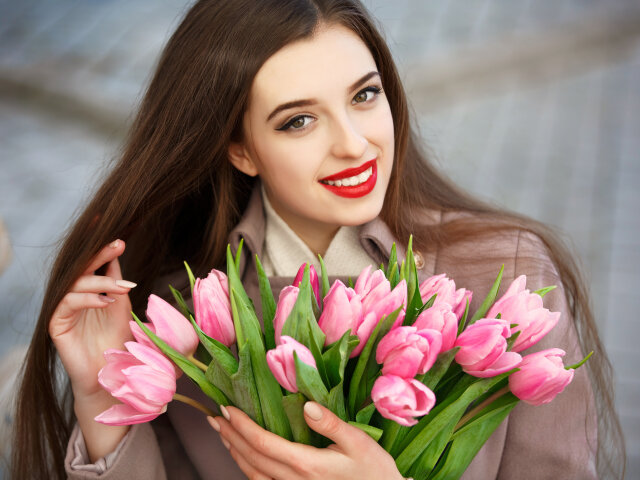 Happy smiling girl with spring tulips flowers outdoors