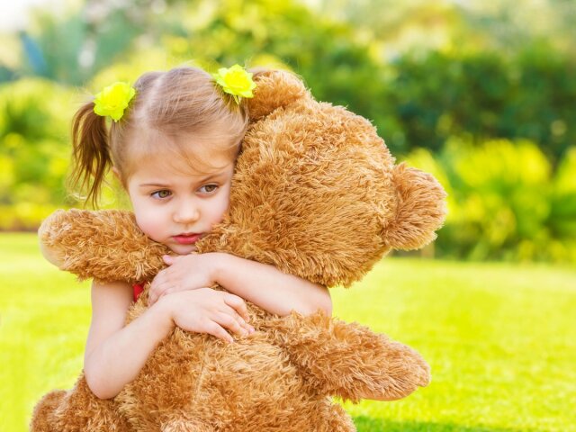 Little cute sad girl holding in hands brown teddy bear, upset ch