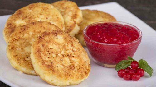 Delicious homemade cheese pancakes with berry jam in white plate