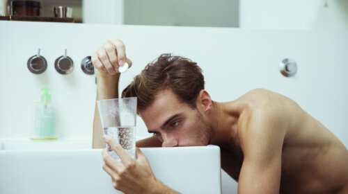 Hungover man watching effervescent tablets in bathroom