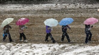 Local residents hold umbrellas as they walk on street as it snows in Shanghai