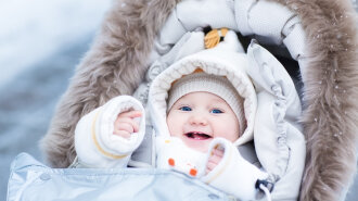Happy laughing baby girl enjoying a walk in a snowy winter parl