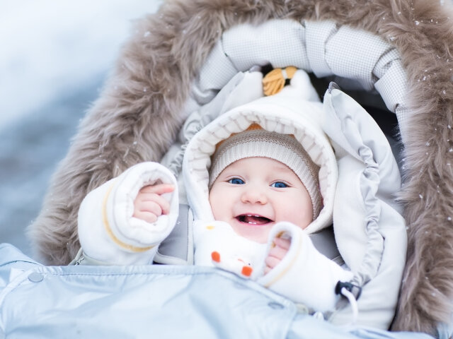 Happy laughing baby girl enjoying a walk in a snowy winter parl