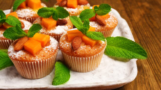 Tasty pumpkin muffins on wooden table