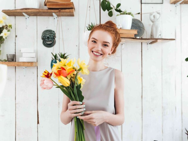 Cheerful young woman with pretty bouquet looking camera