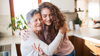 A teenage girl with grandmother at home, hugging.