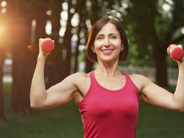 Portrait of cheerful aged woman in fitness wear exercising with