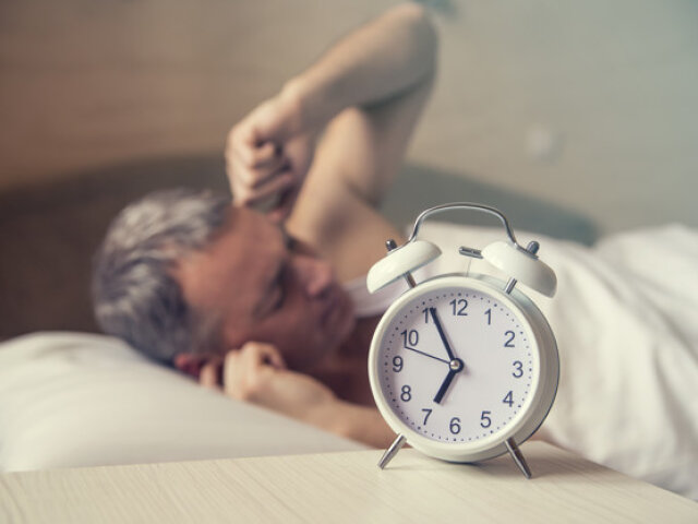 sleeping man disturbed by alarm clock early morning. Angry man i